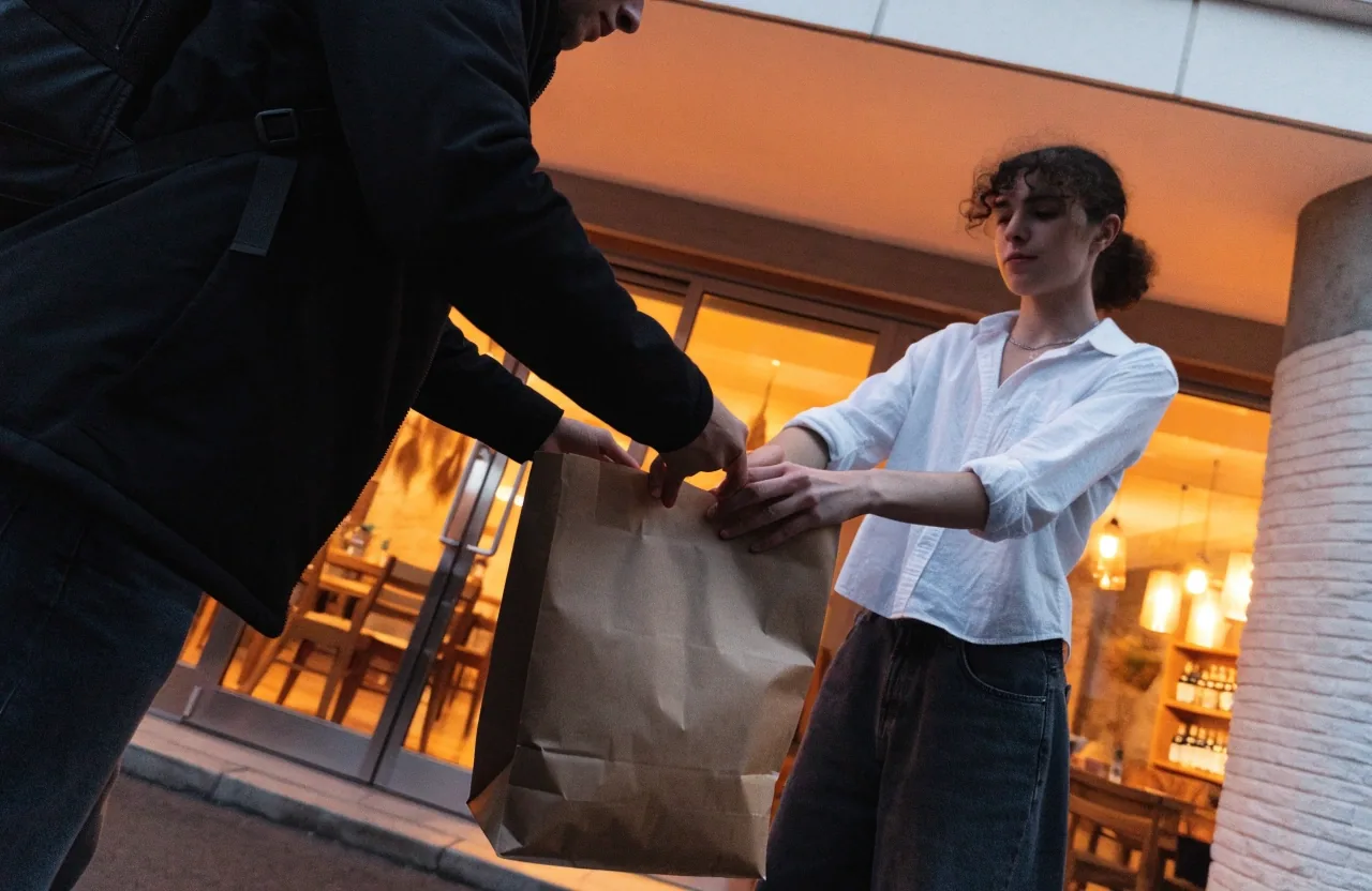 Evening delivery handover outside a Guzman y Gomez restaurant